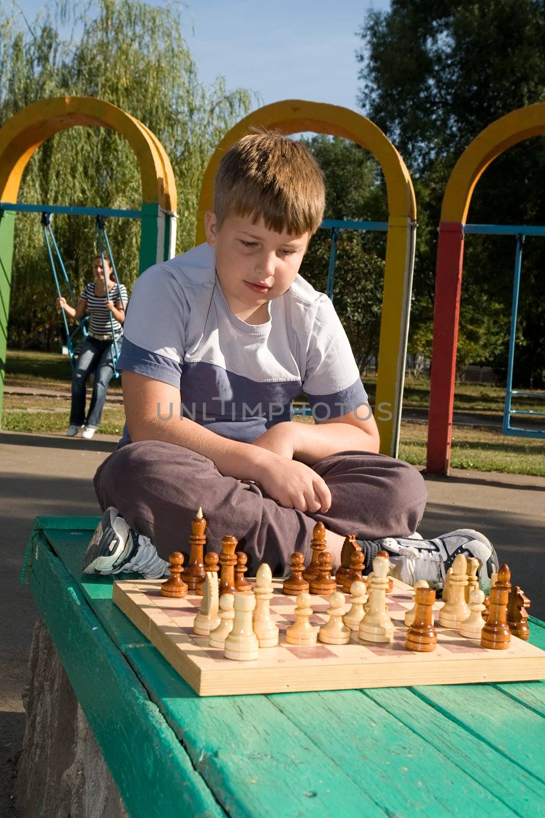 little boy play a chess in park