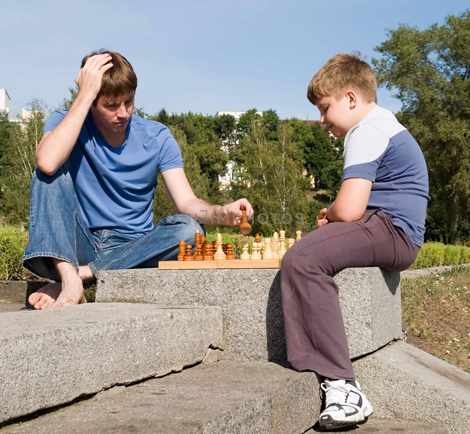 Father playing chess with his boy in park