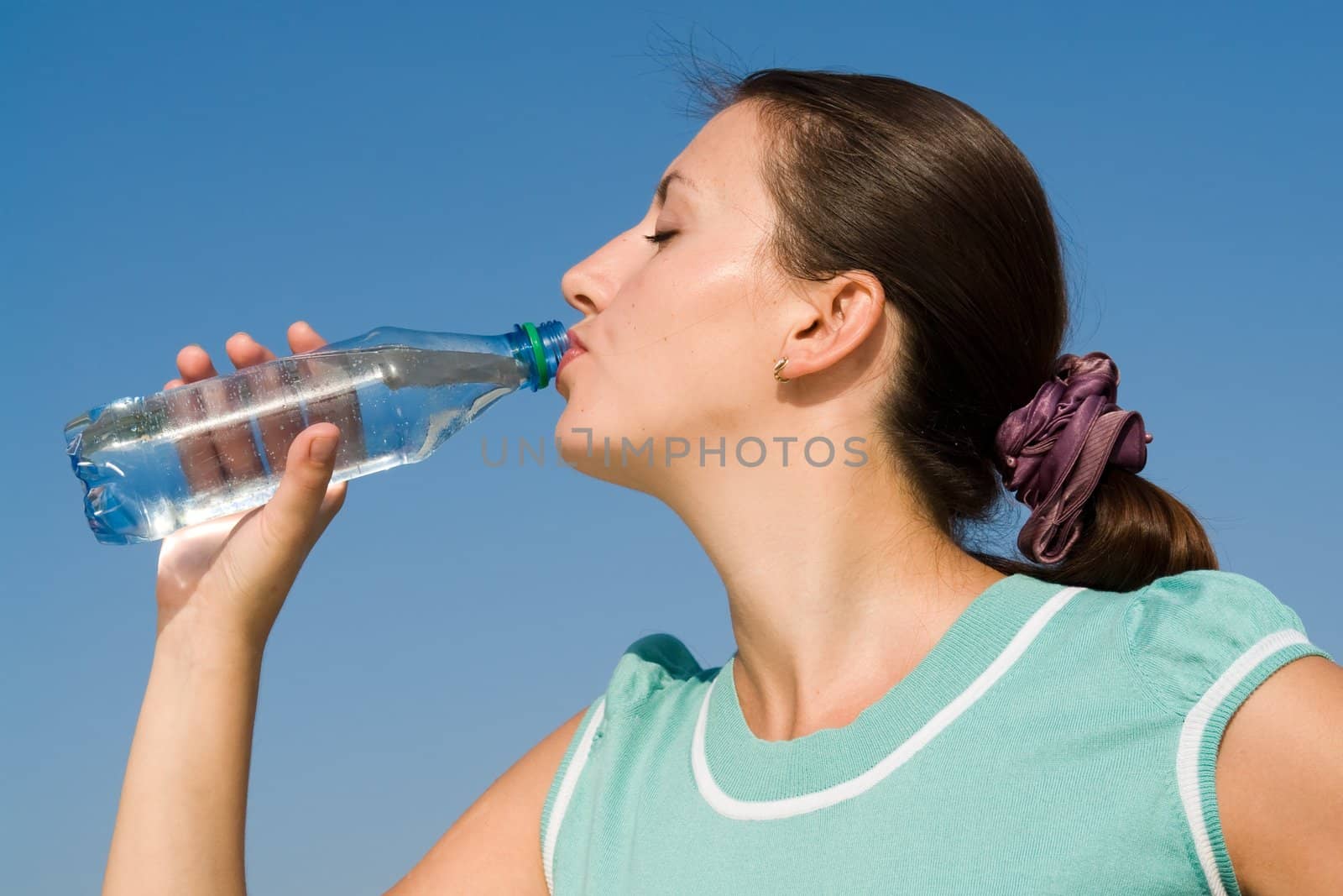 beautiful woman drinks water on a blue sky