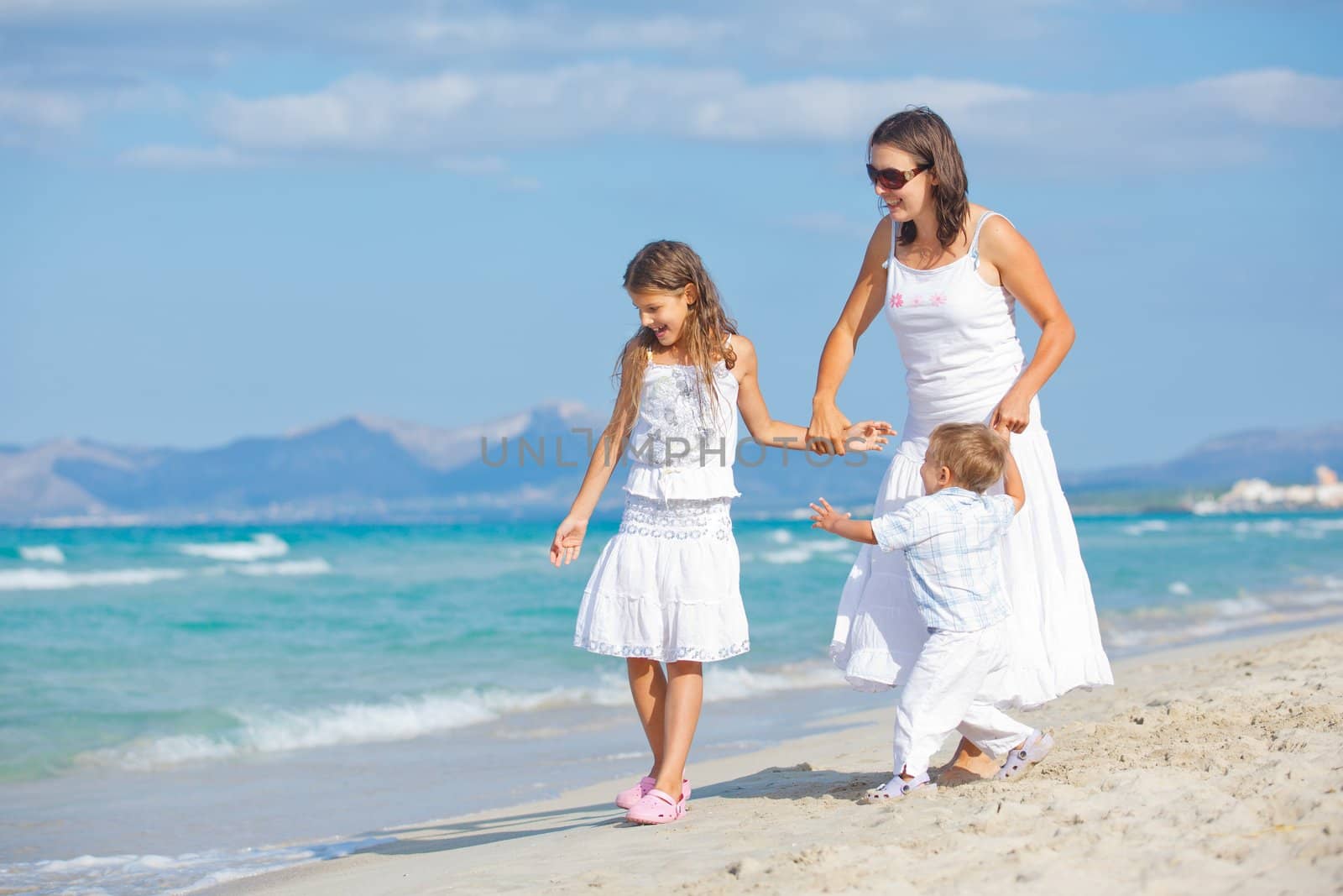 Young mother with her two kids on beach vacation by maxoliki