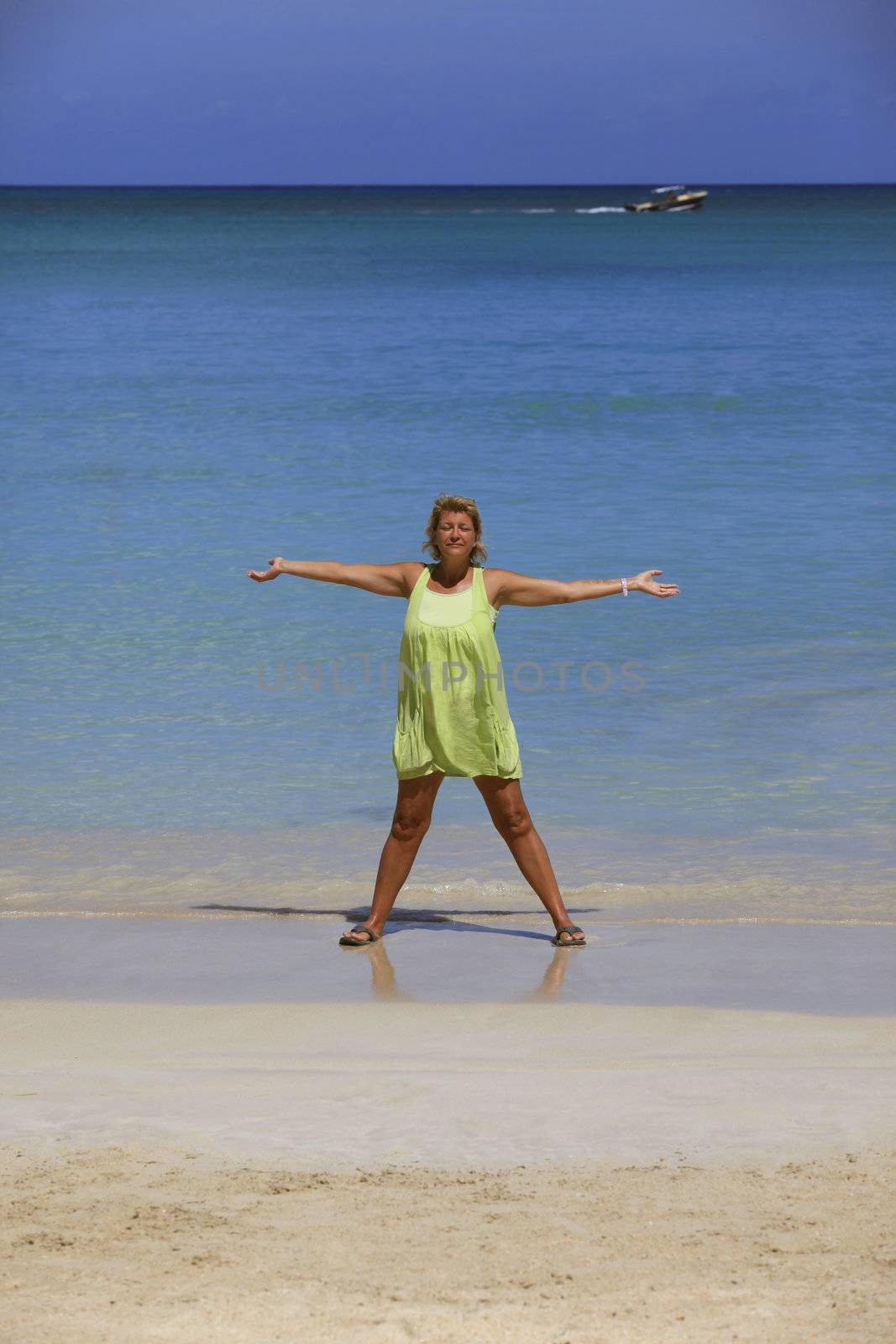 Adult woman with arms raised standing on beach