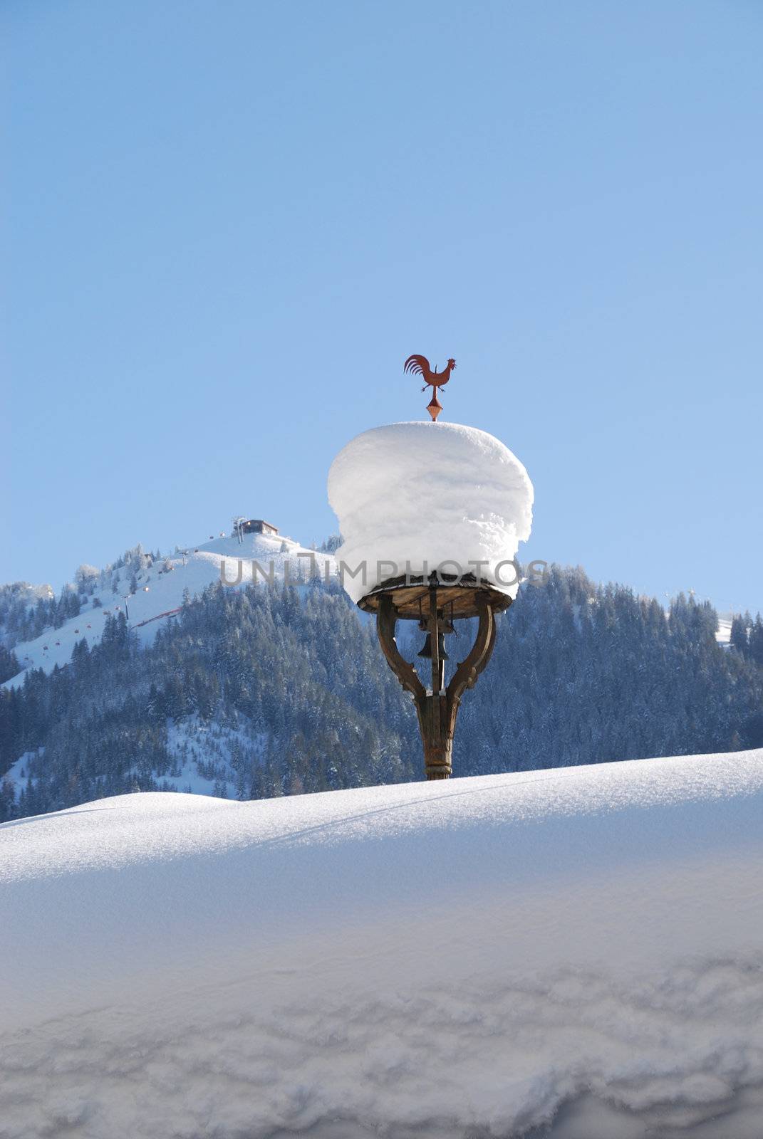 Weather cock on snow covered roof in Austria