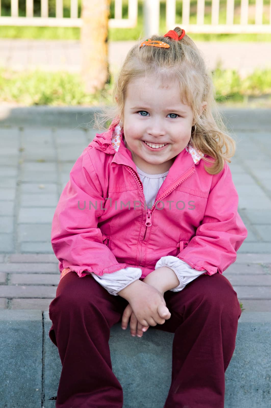 girl in a pink jacket, sitting and smiling