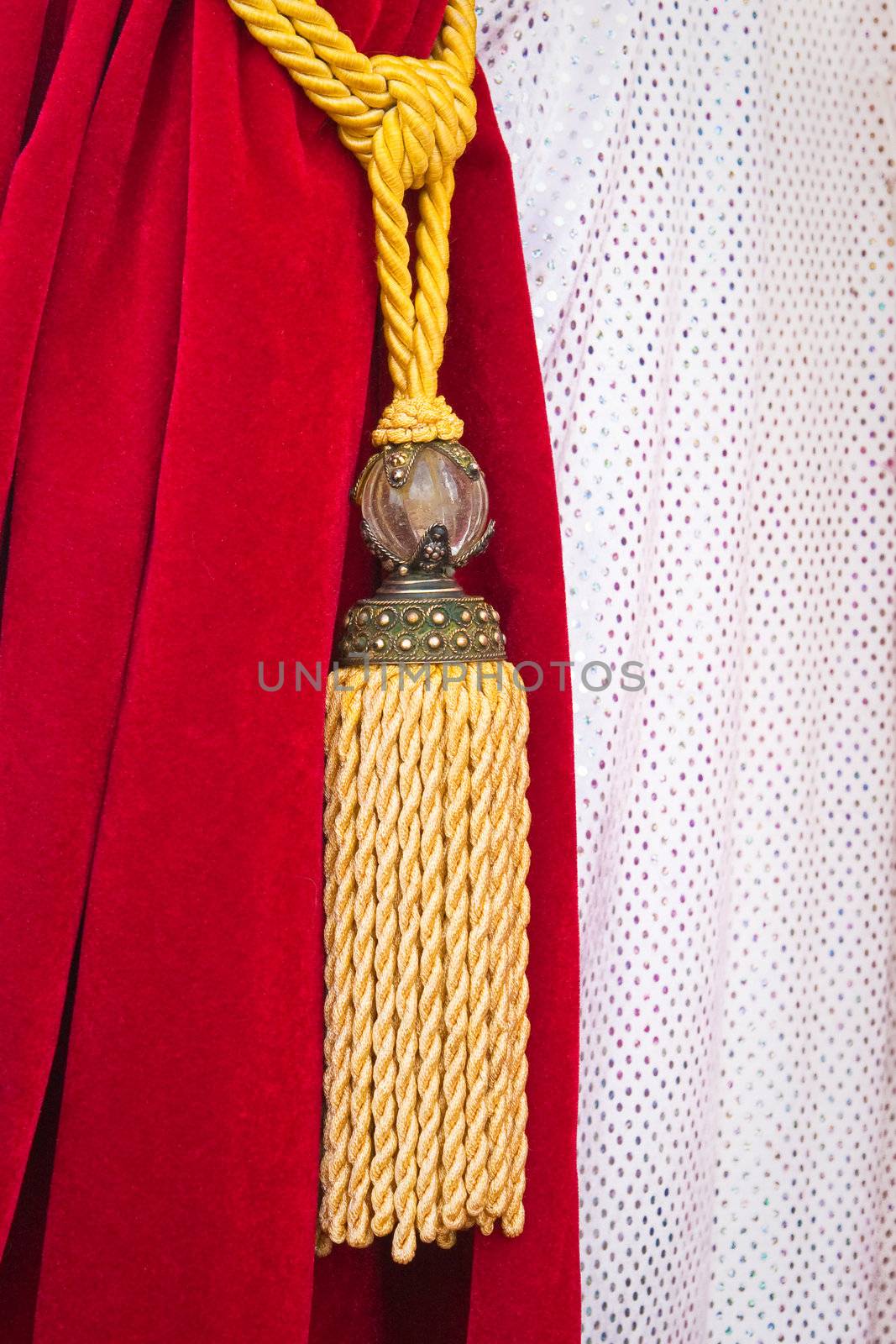 A nice red velvet curtain tied back by a string and tassel