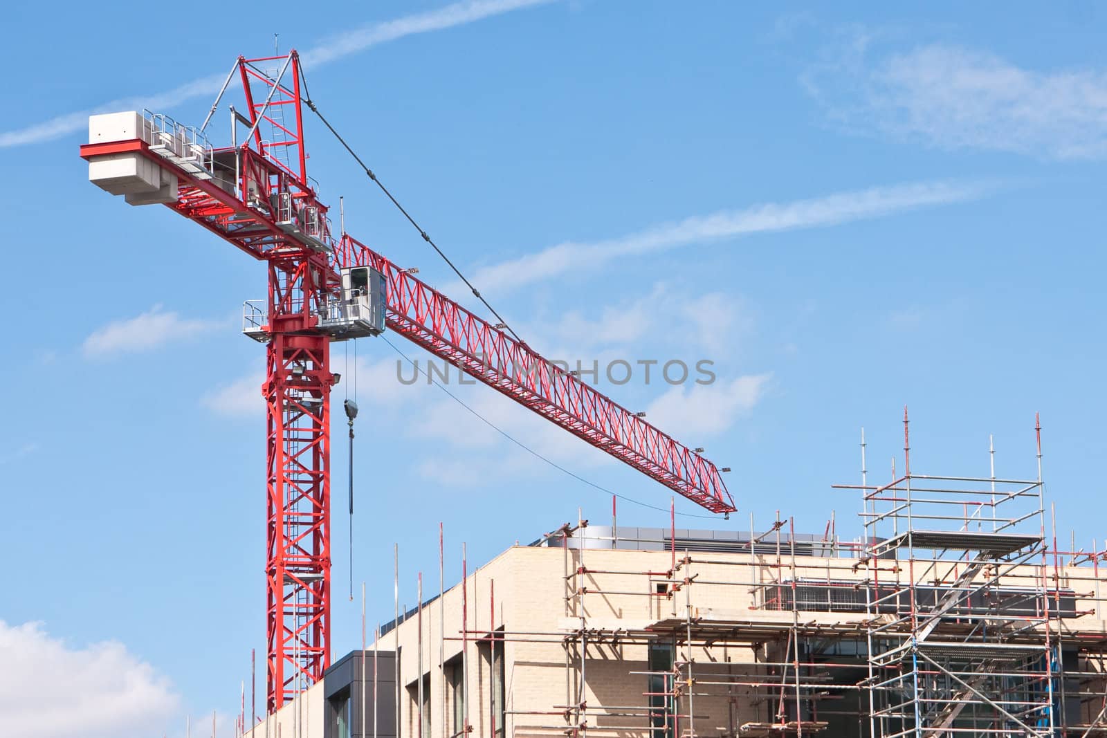 A red crane at a construction site on a sunny day