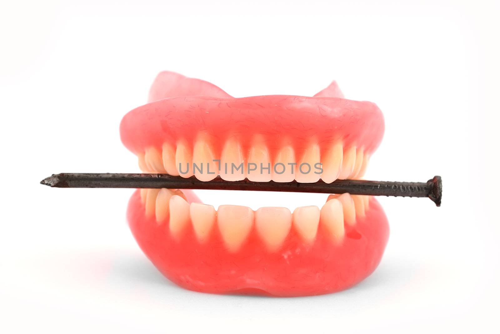 Plastic dentures and nail on a white background