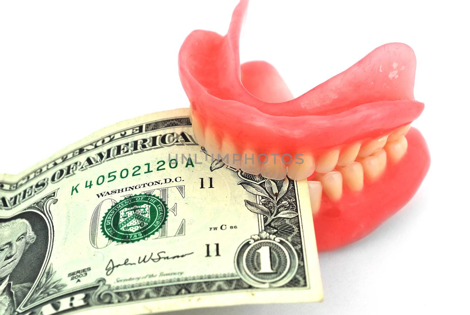 Plastic dentures and dollar on a white background