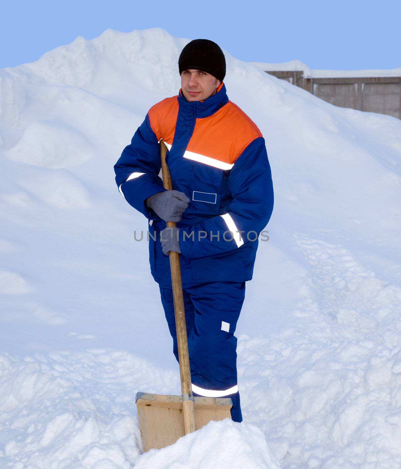 Worker in the winter suit consisting of a jacket and trousers against the backdrop of the snow