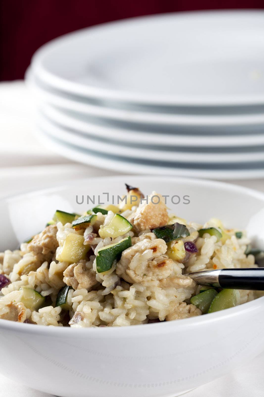 Zucchini and risotto main entree with plates in the background.