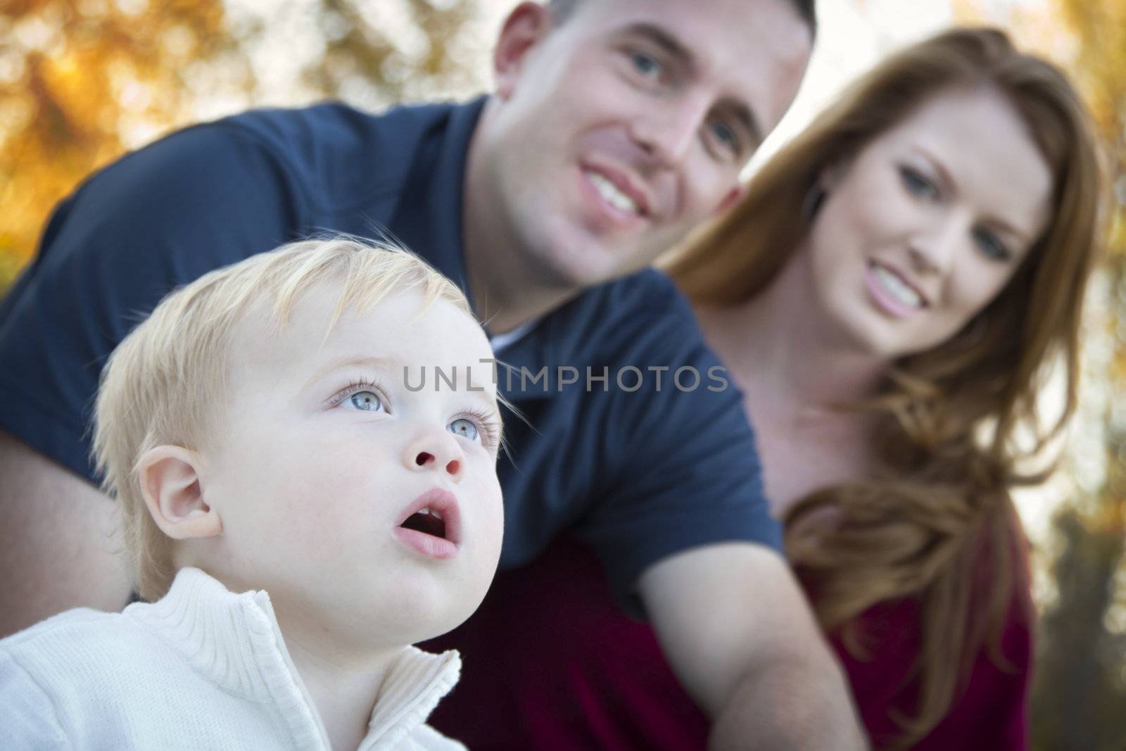 Cute Child Boy Looks Up to the Sky as Young Parents Smile.