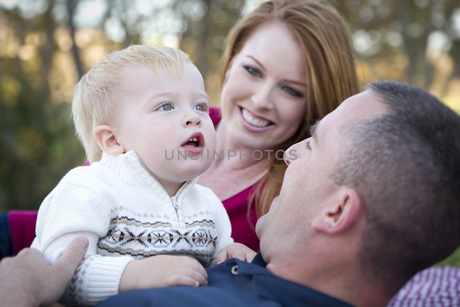 Cute Child Boy Looks Up to the Sky as Young Parents Smile.