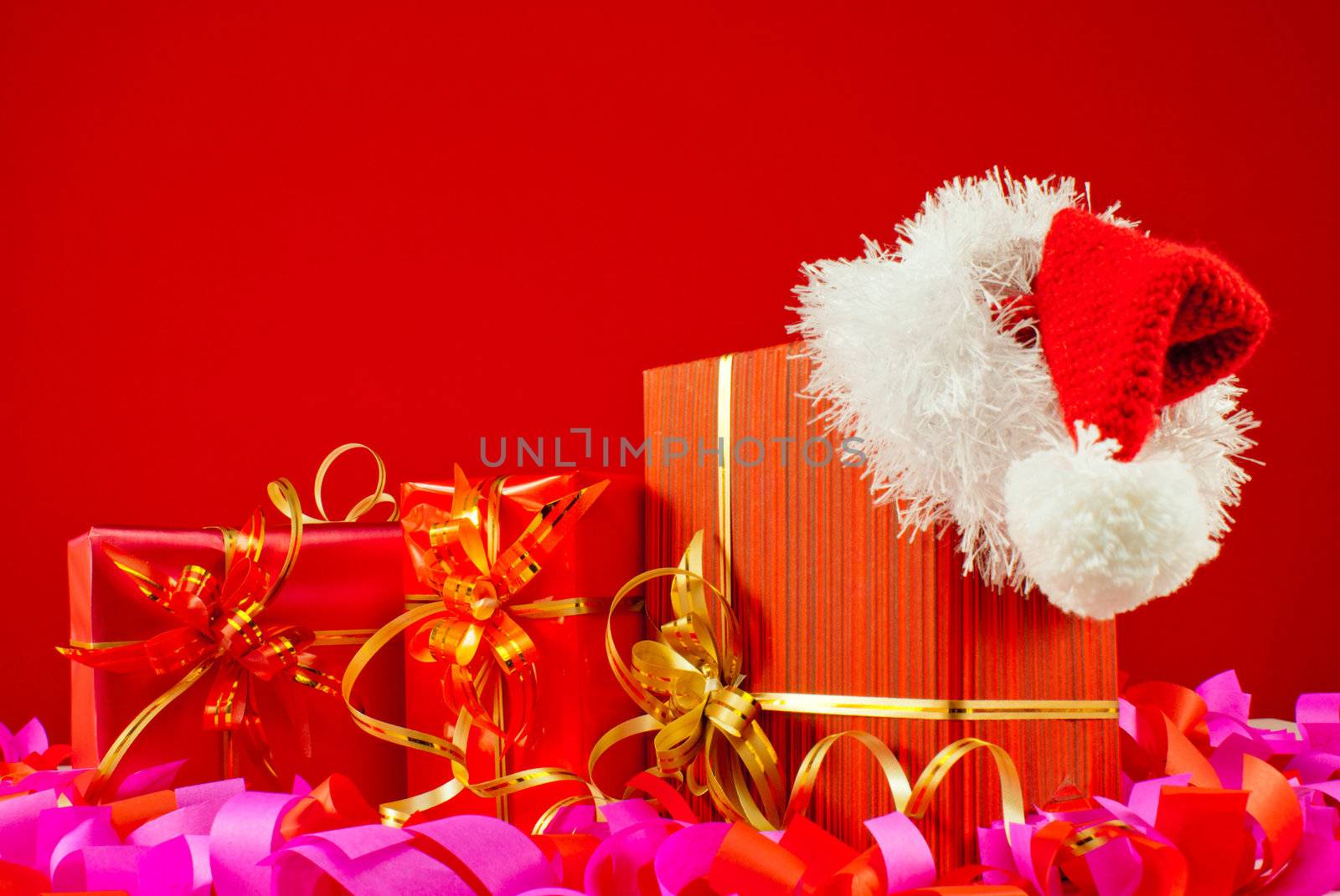 Christmas presents with Santa's hat against red background
