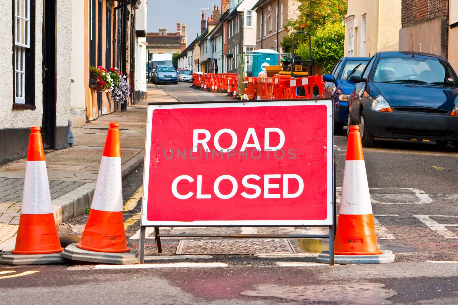 A sign indicating a closed road with traffic cones in an english town