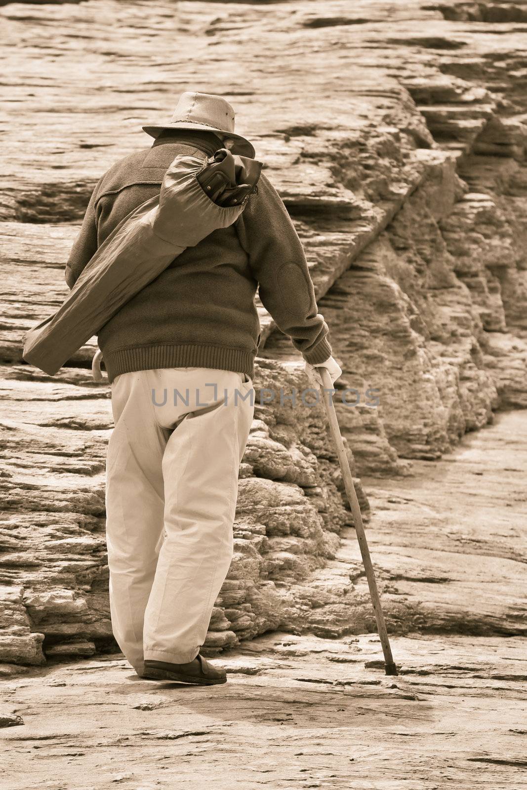Old man walking with a stick on rocks