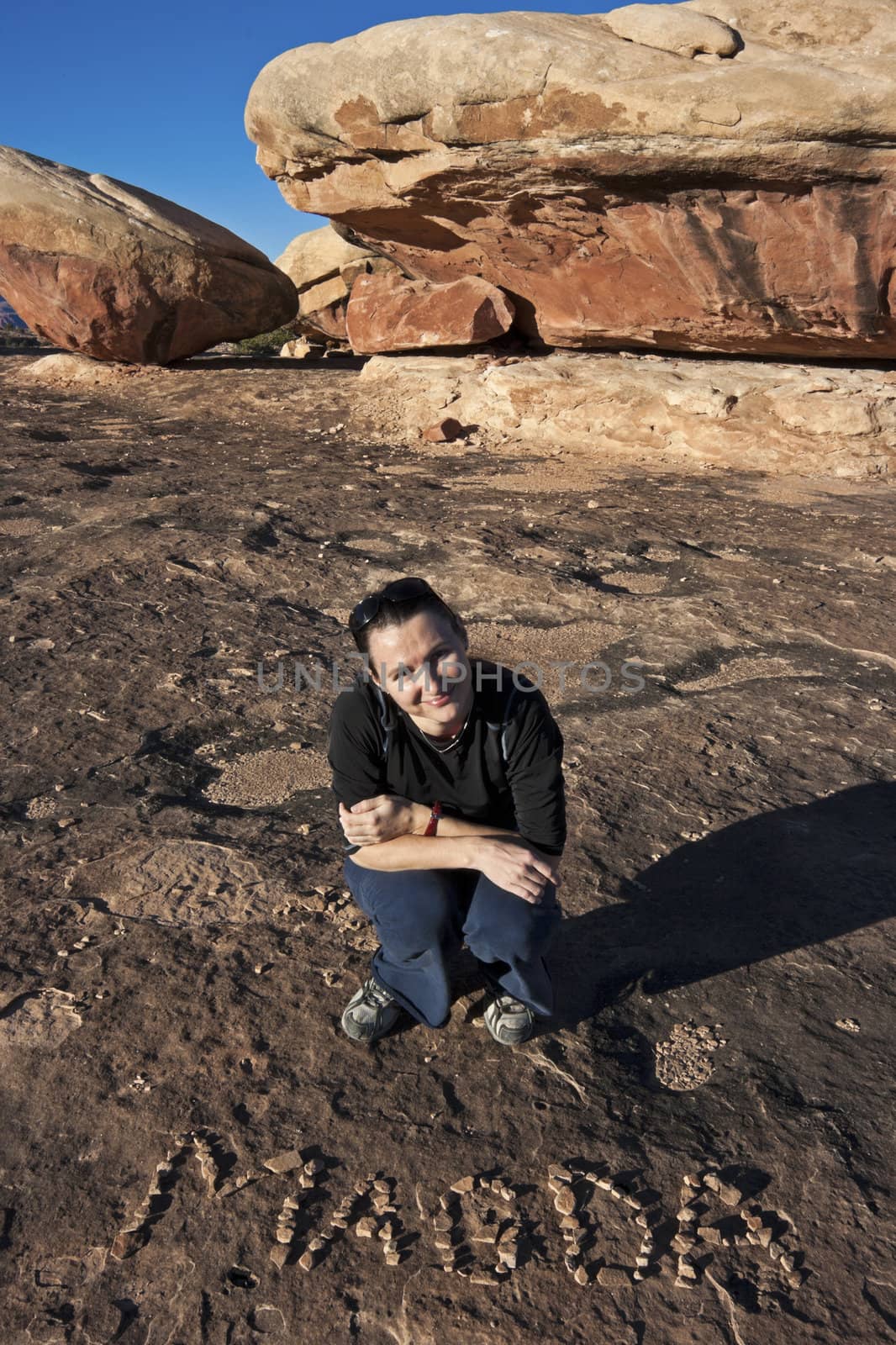 Smiling girl with her name written with little stones. Canyonlands National Park, Utah, USA.