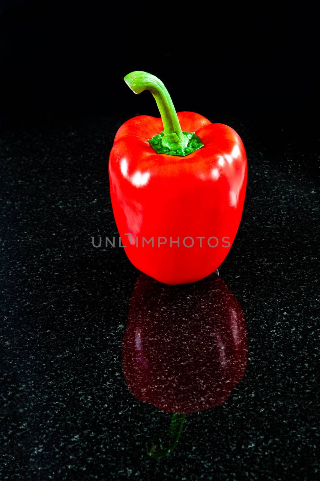 A perfect red bell pepper reflected in granite