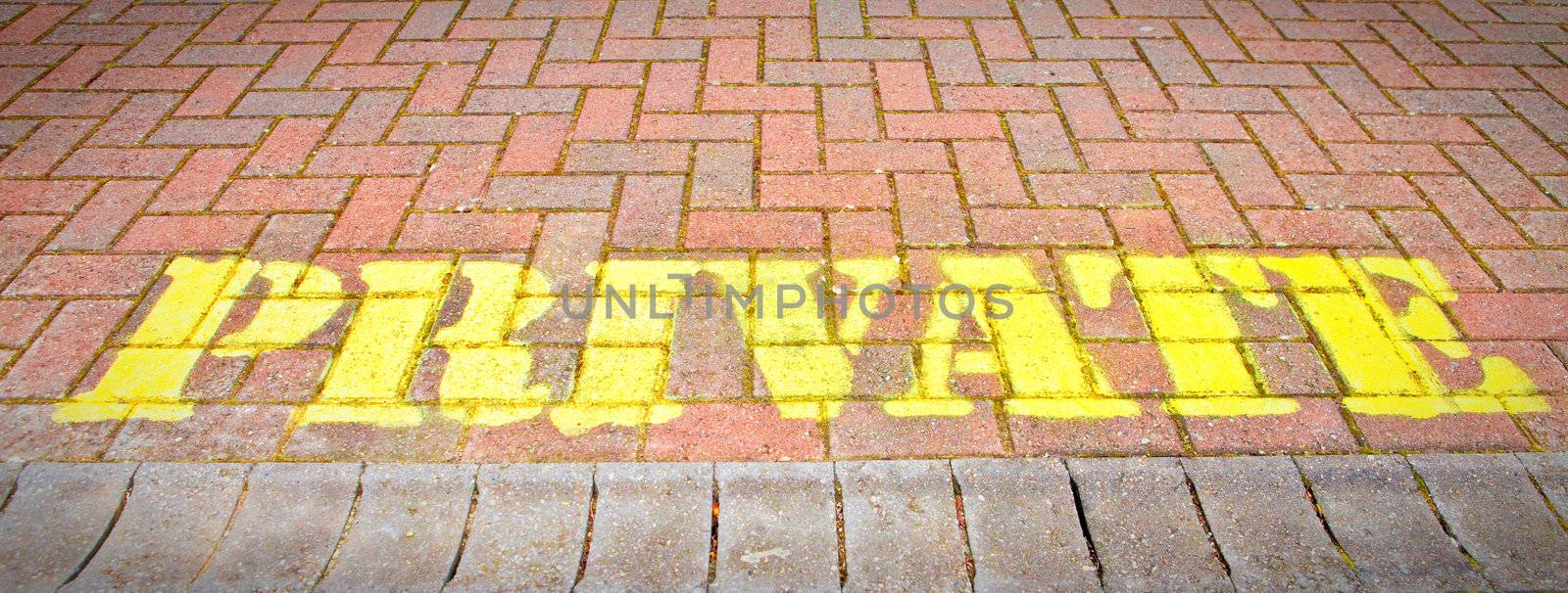 Pivate written in yellow paint on brickwork