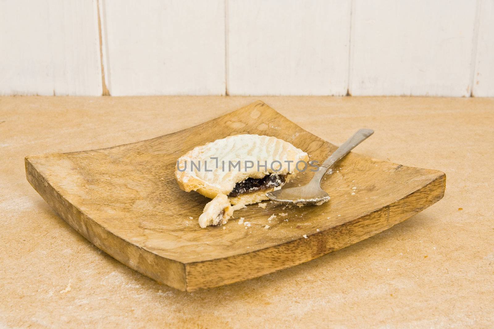 Unusual rustic image of a half-eaten mince pie on a wooden plate