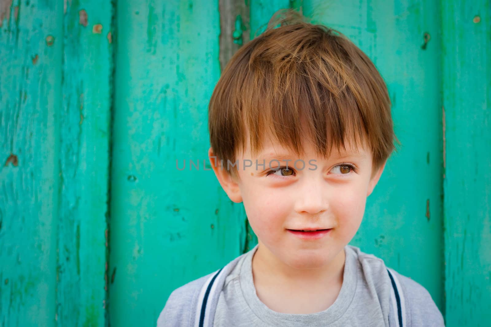 An adorable three year old boy in front of a vibrant blue background