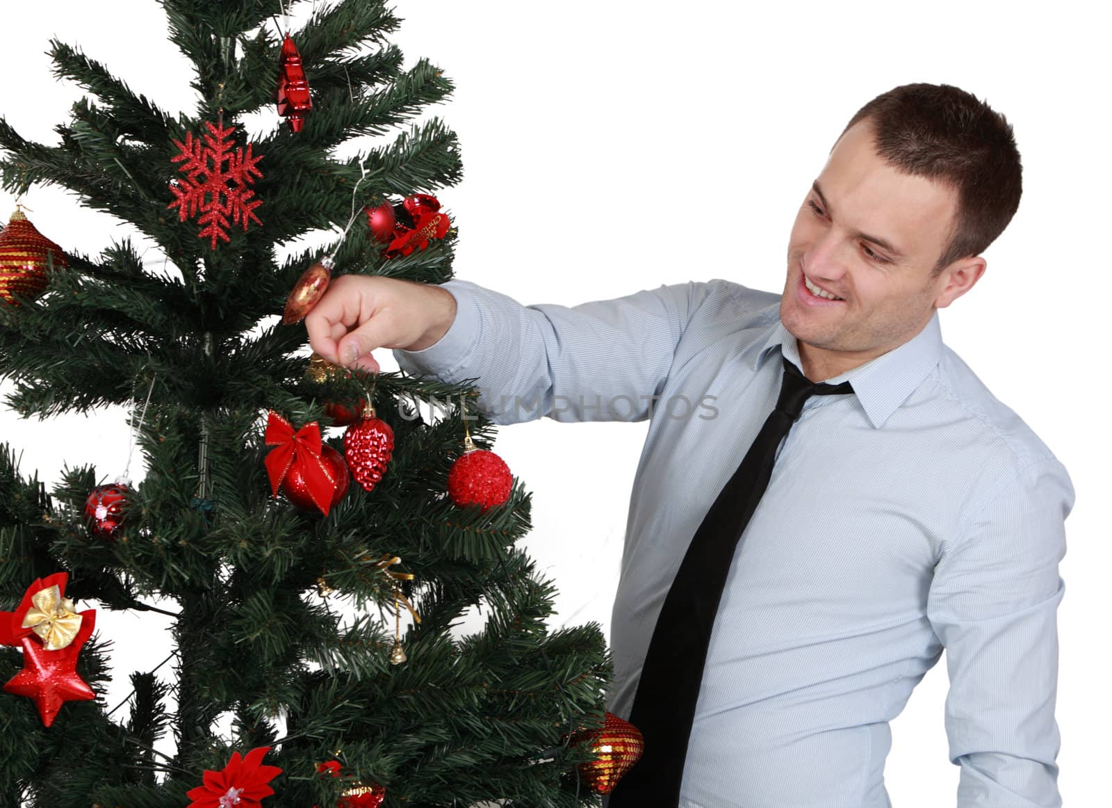 A young man decorating a Christmas tree isolated against a white background.