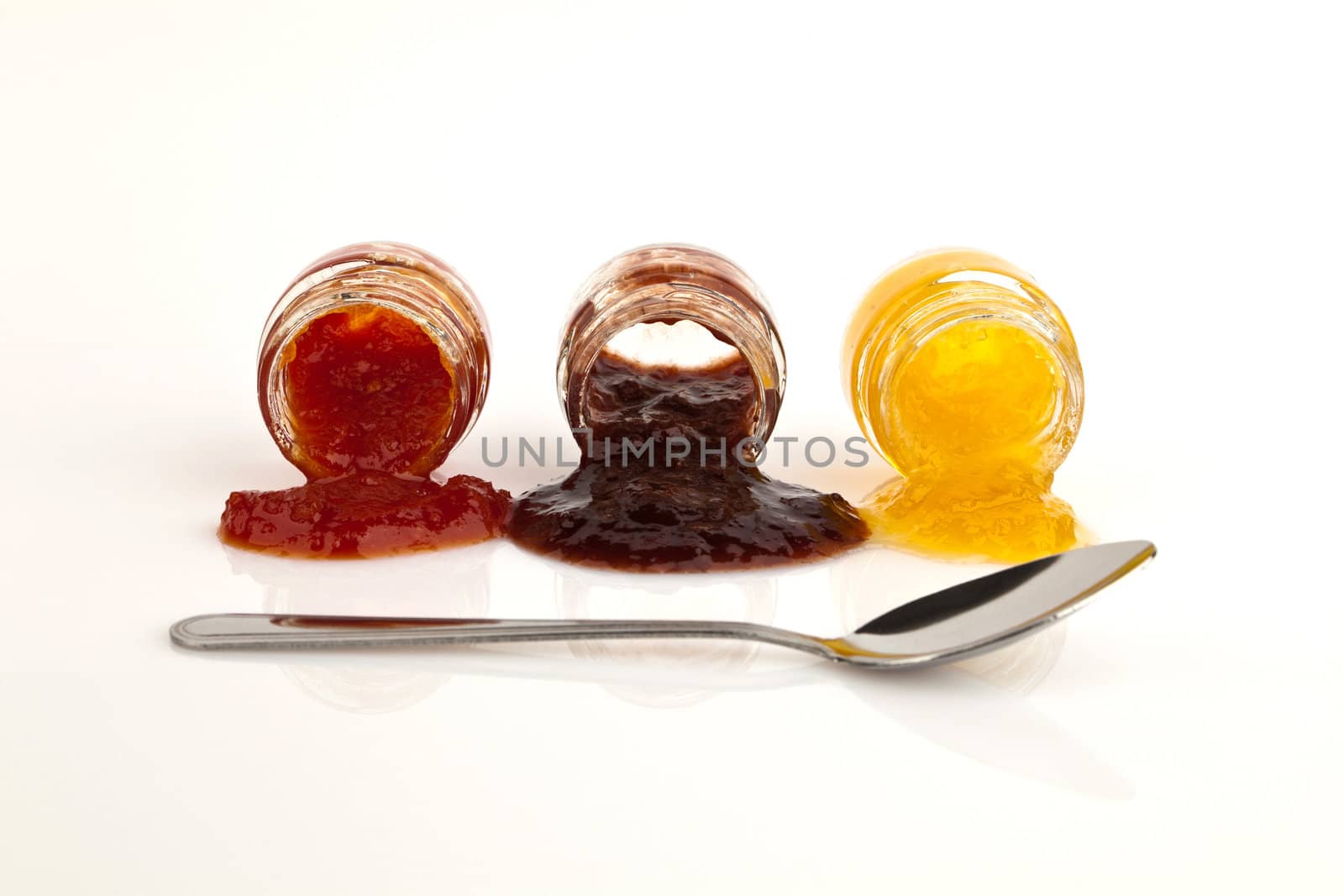 Peach, plum and tomato in glass with metal spoon isolated on white.