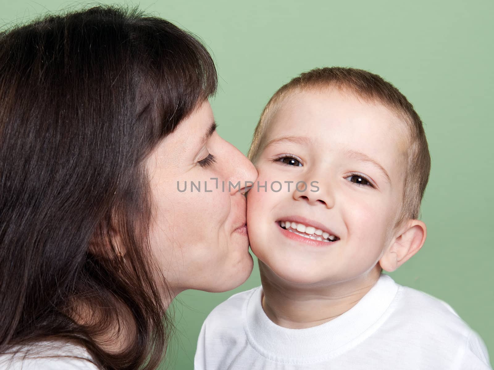 Mother kissing smiling child - family happiness