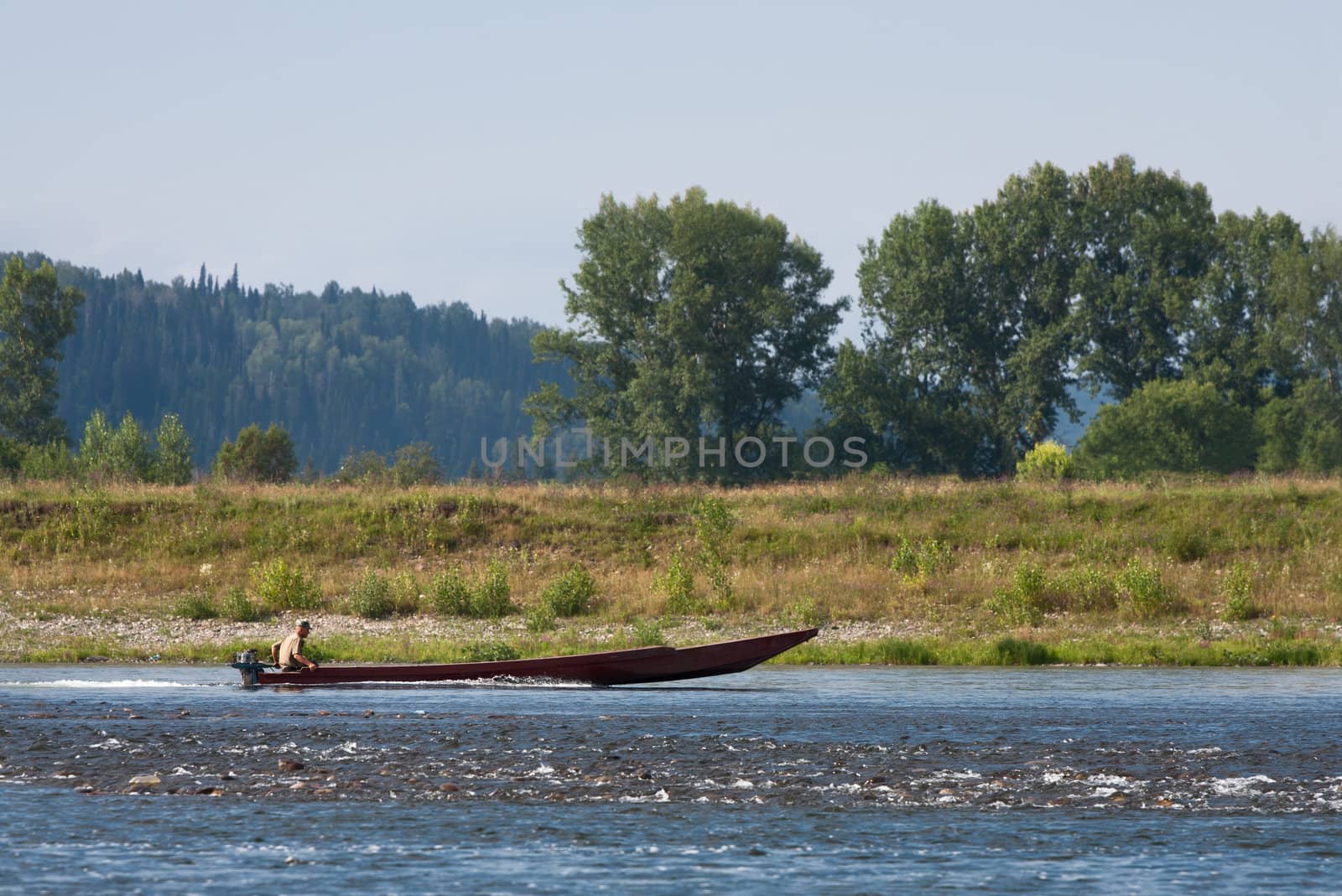 Man floats on a long wooden boat on a mountain river