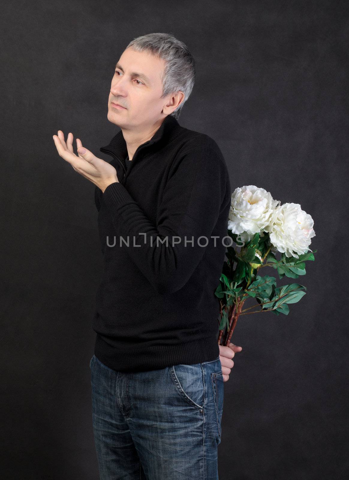 Man hiding a bouquet of flowers on gray background