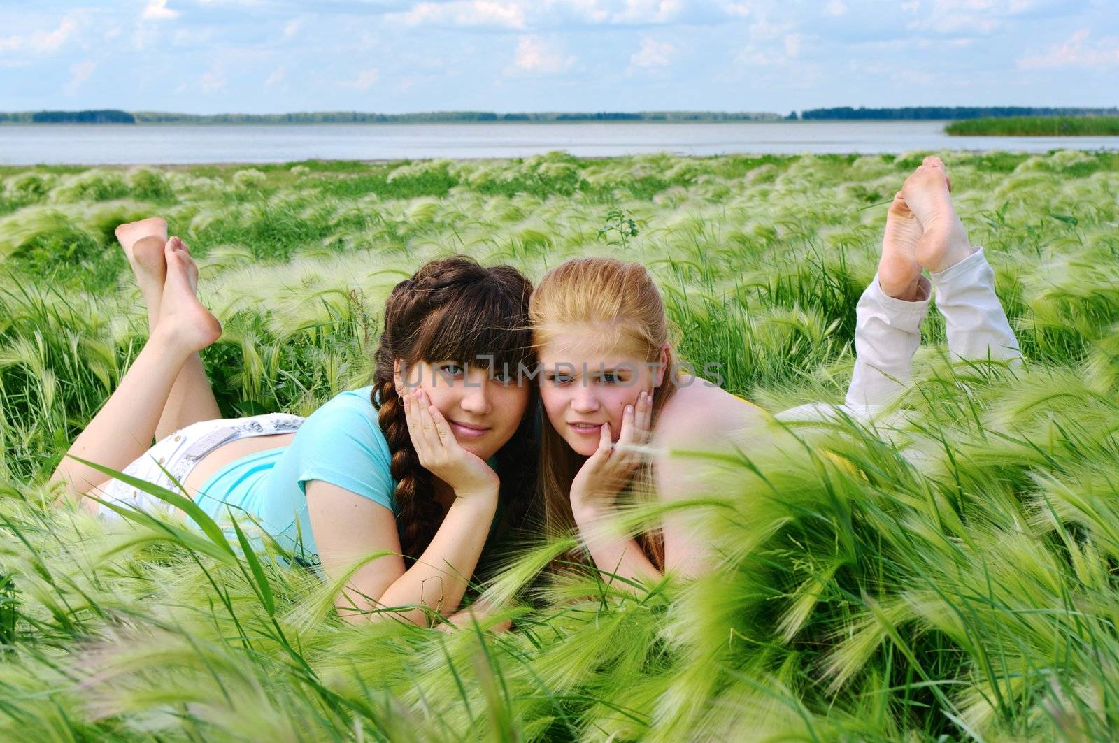 two girls lie on the bank of lake