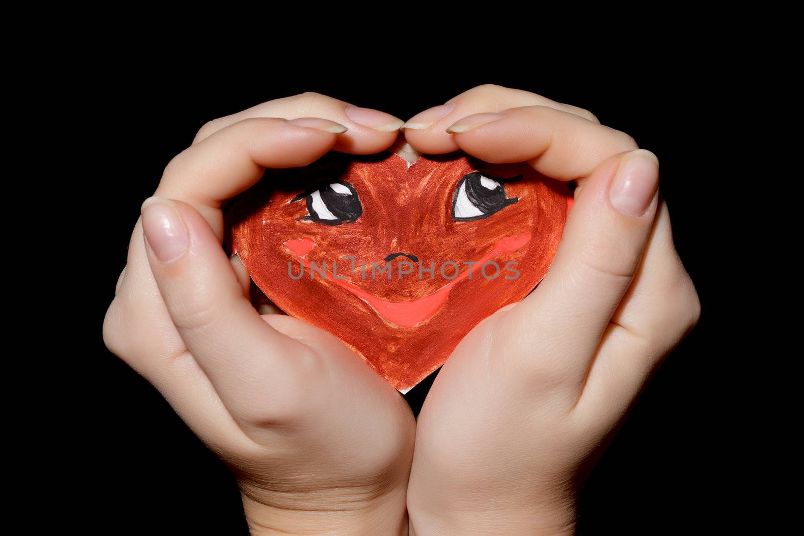 Smiling heart in hands on black background