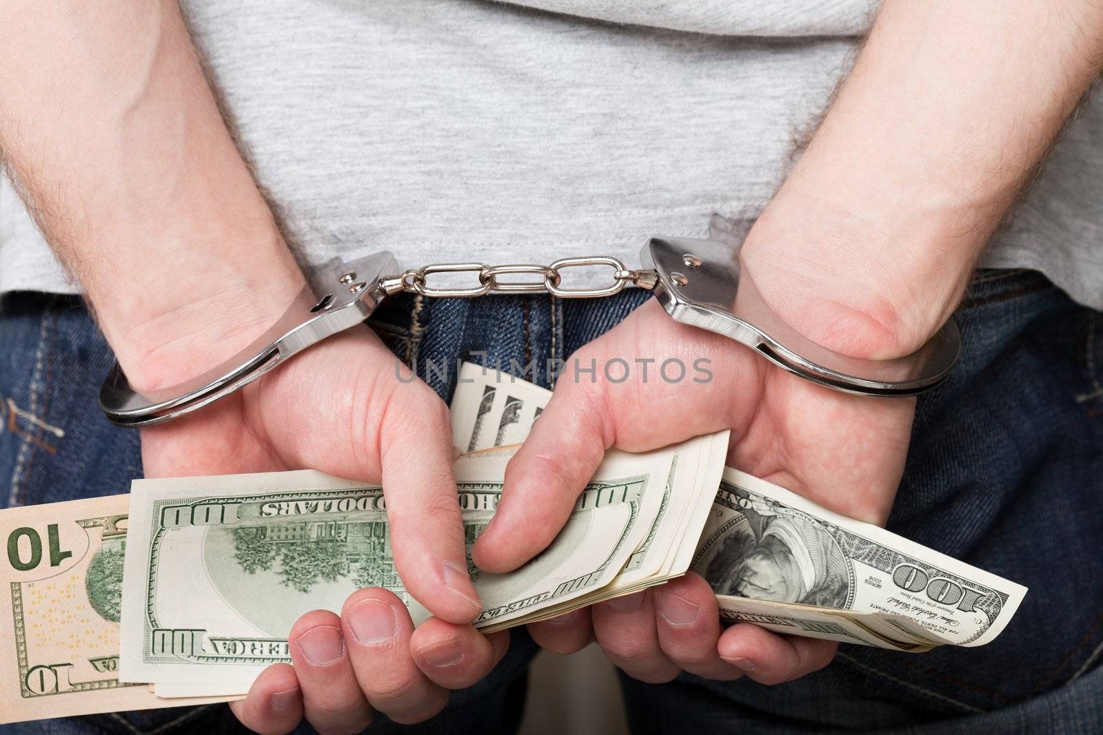 Handcuffs on hands holding money by ia_64