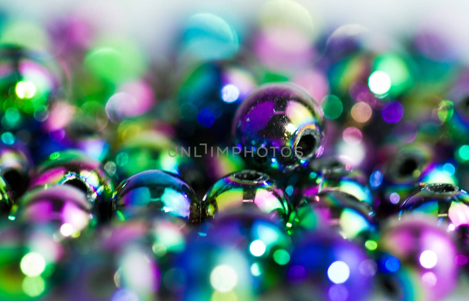 Blue beads on bluish background with colorful reflection and bokeh in landscape orientation