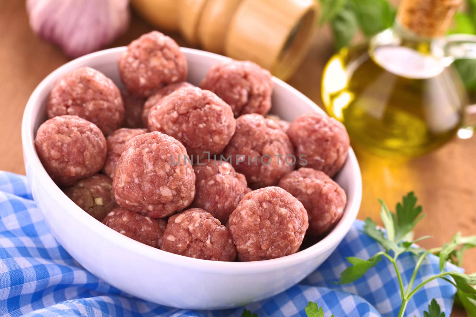 Raw meatballs with garlic in a white bowl (Selective Focus, Focus on the meatballs in the front)