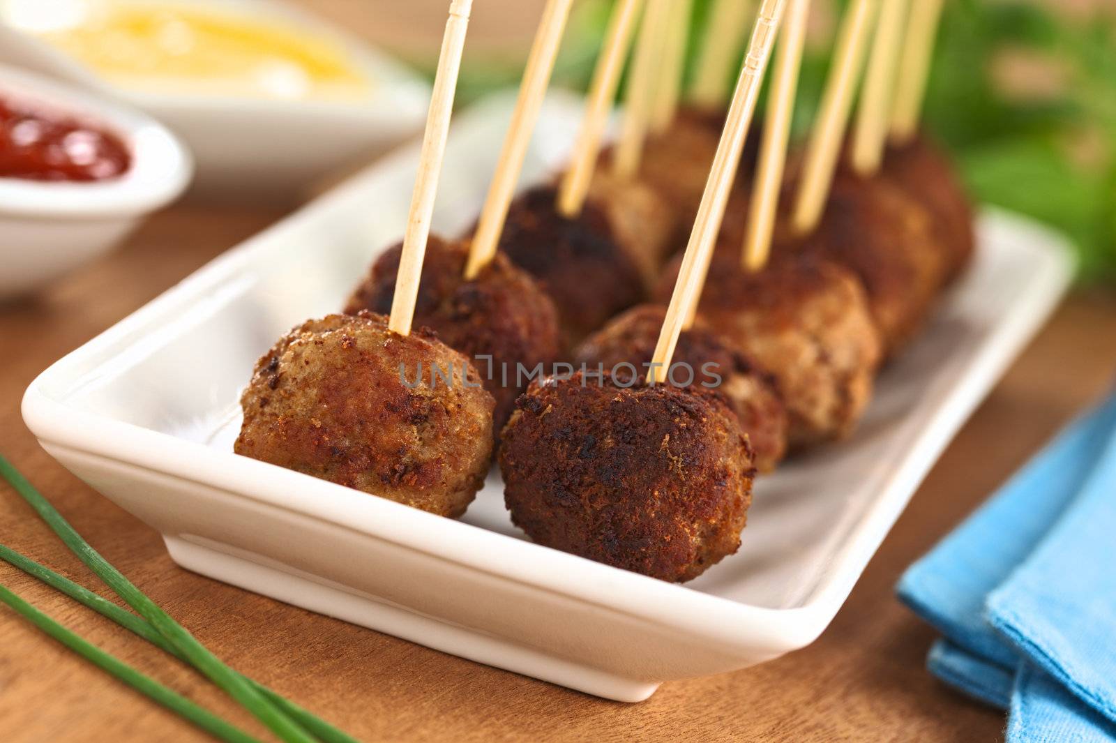 Meatball appetizers with toothpicks and sauces on the side (Selective Focus, Focus on the first two meatballs)