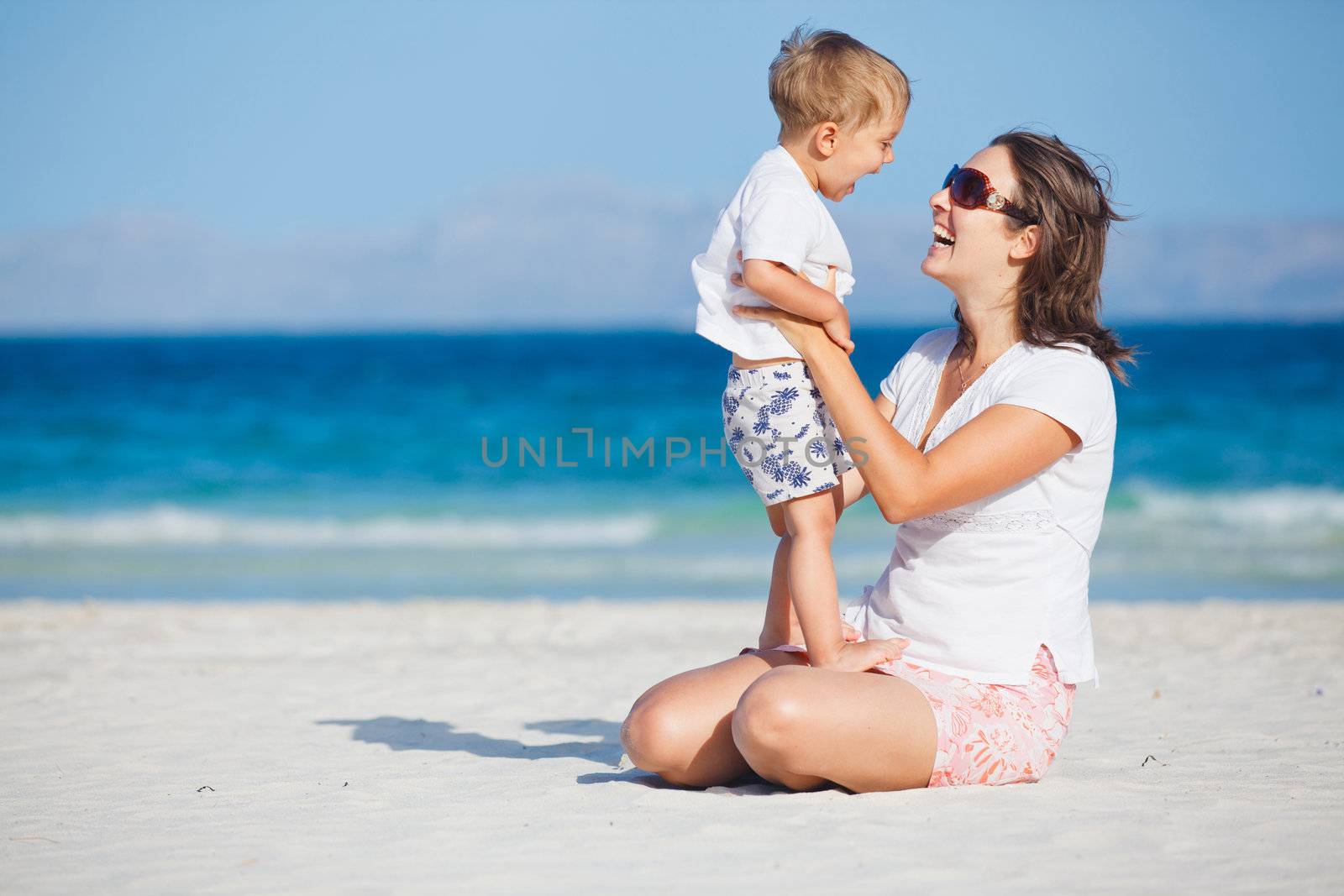 Young mother and her son playing happily at pretty beach