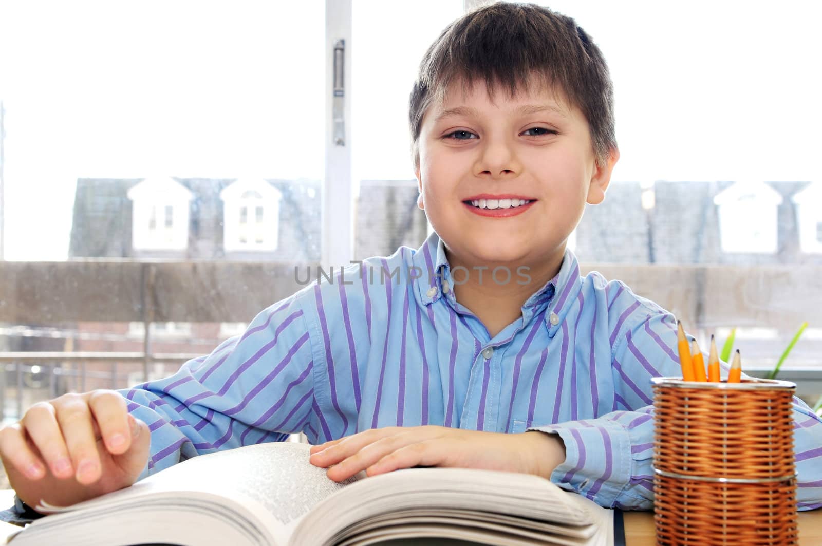 Happy school boy studying with a book