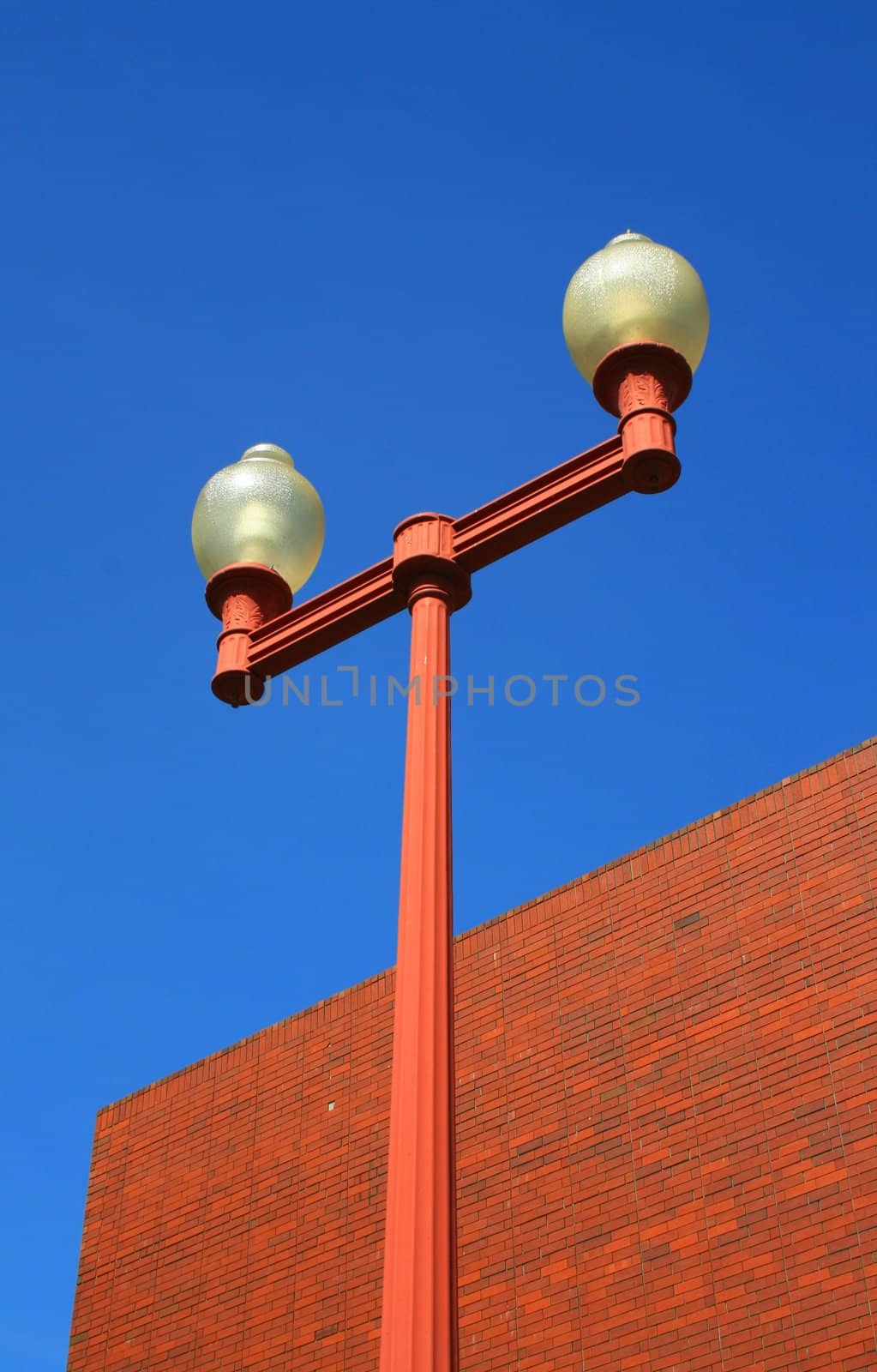 Street light pole next to a brick wall.
