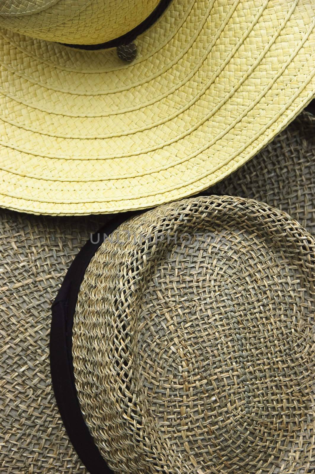 Close-up of two straw hats, one light yellow and the other dark brown
