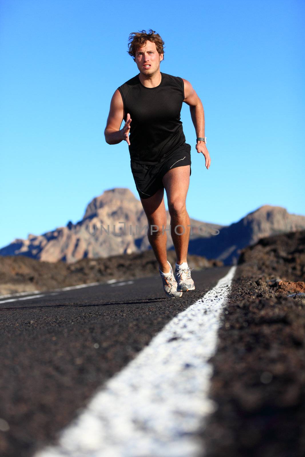 Man running in beautiful nature. Male runner jogging during work out training on mountain road. Young Caucasian fitness model with copy space.