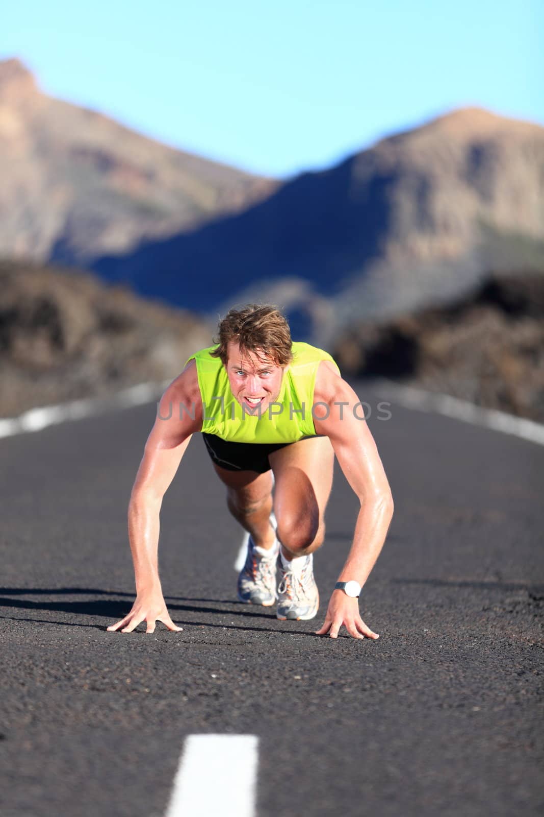 Sprinter ready for sprint. Man runner starting running sprint on road in beautiful mountain nature landscape. Fit Caucasian male fitness model during work out.