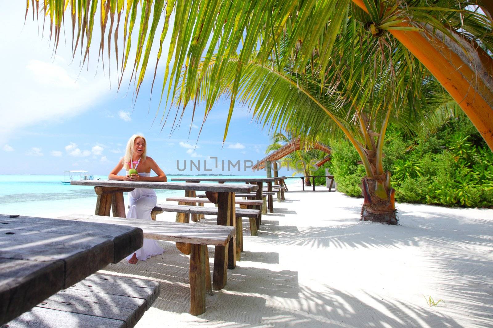 woman sitting in a tropical cafe on the background of a  palm trees and sky and sea