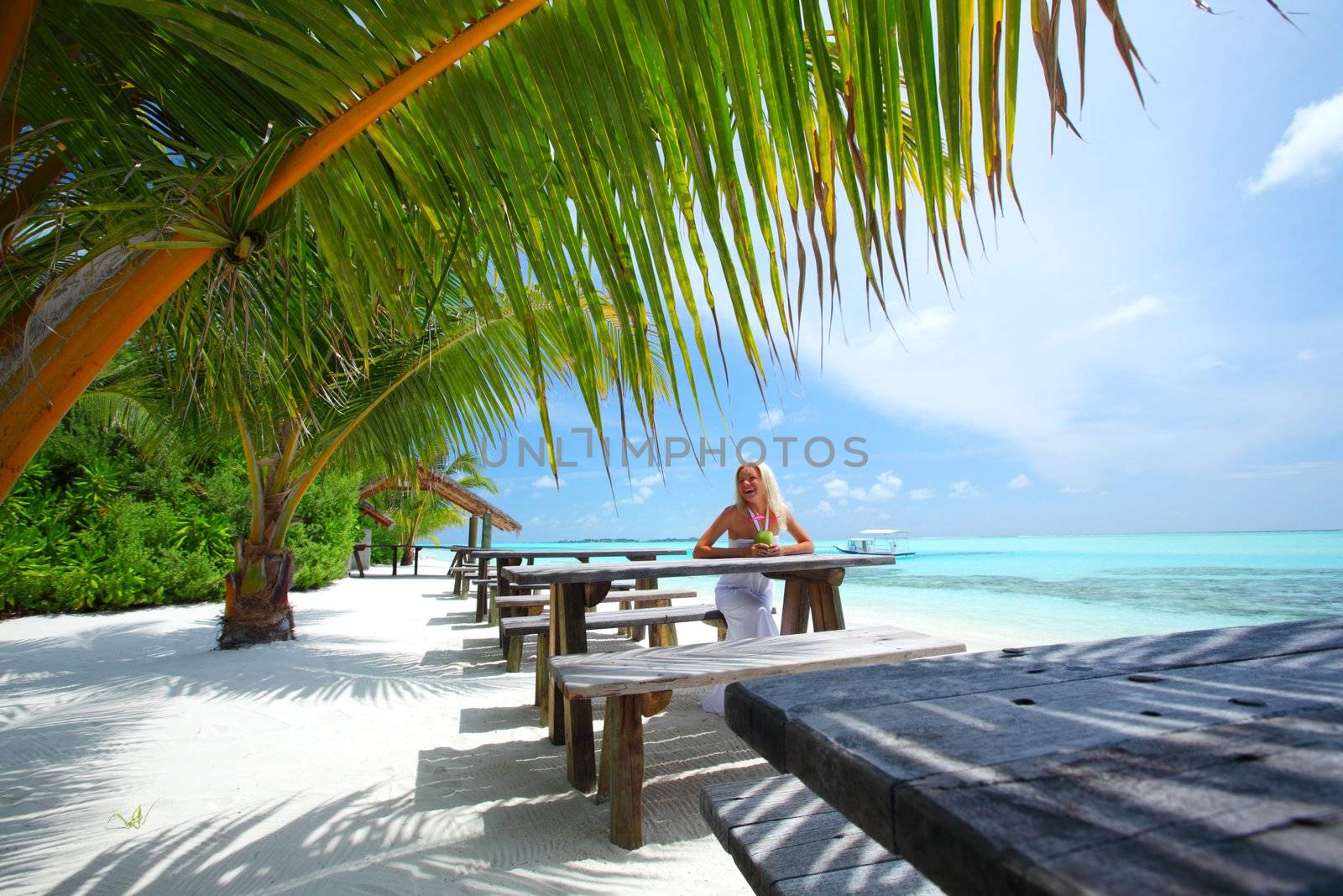 woman sitting in a tropical cafe on the background of a  palm trees and sky and sea