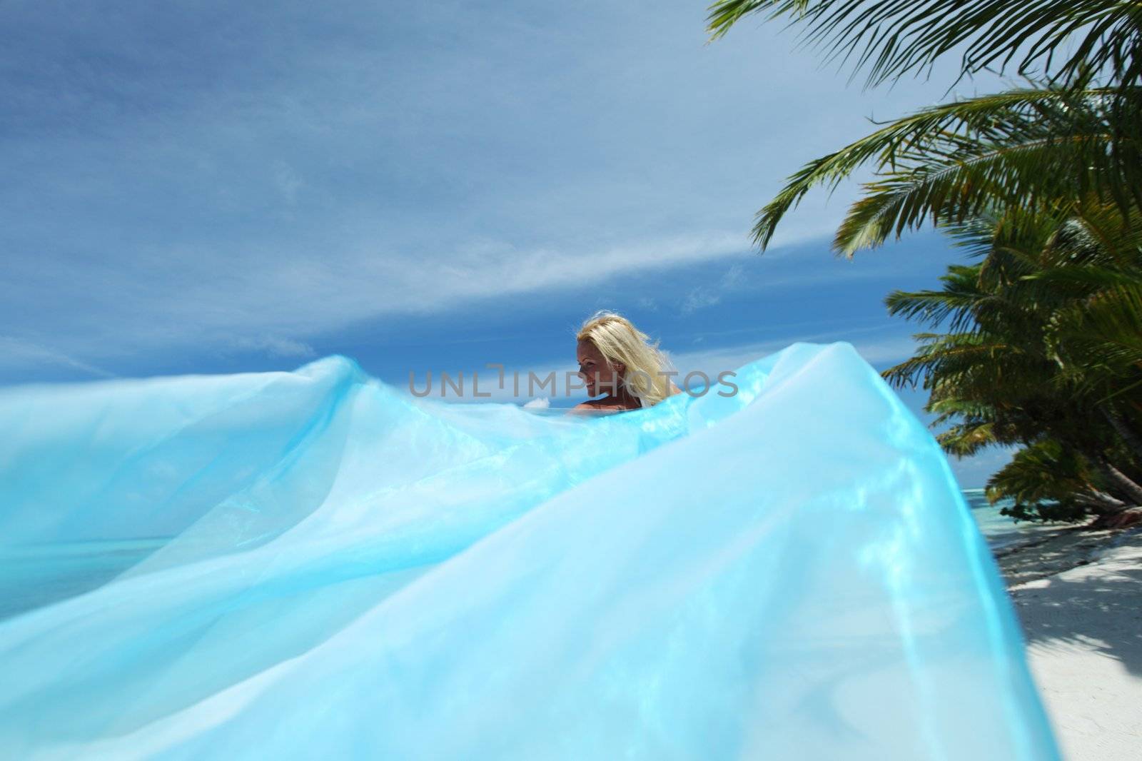 woman with a white fabric in his hands on the beach