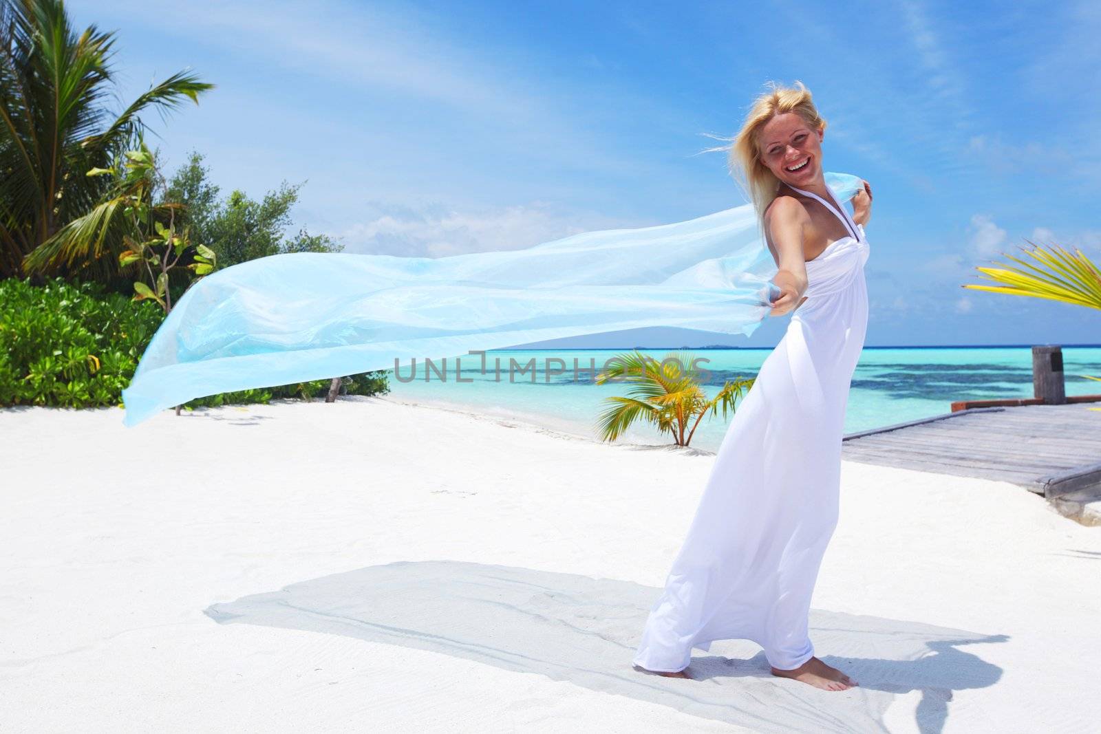 woman with a white fabric in his hands on the beach