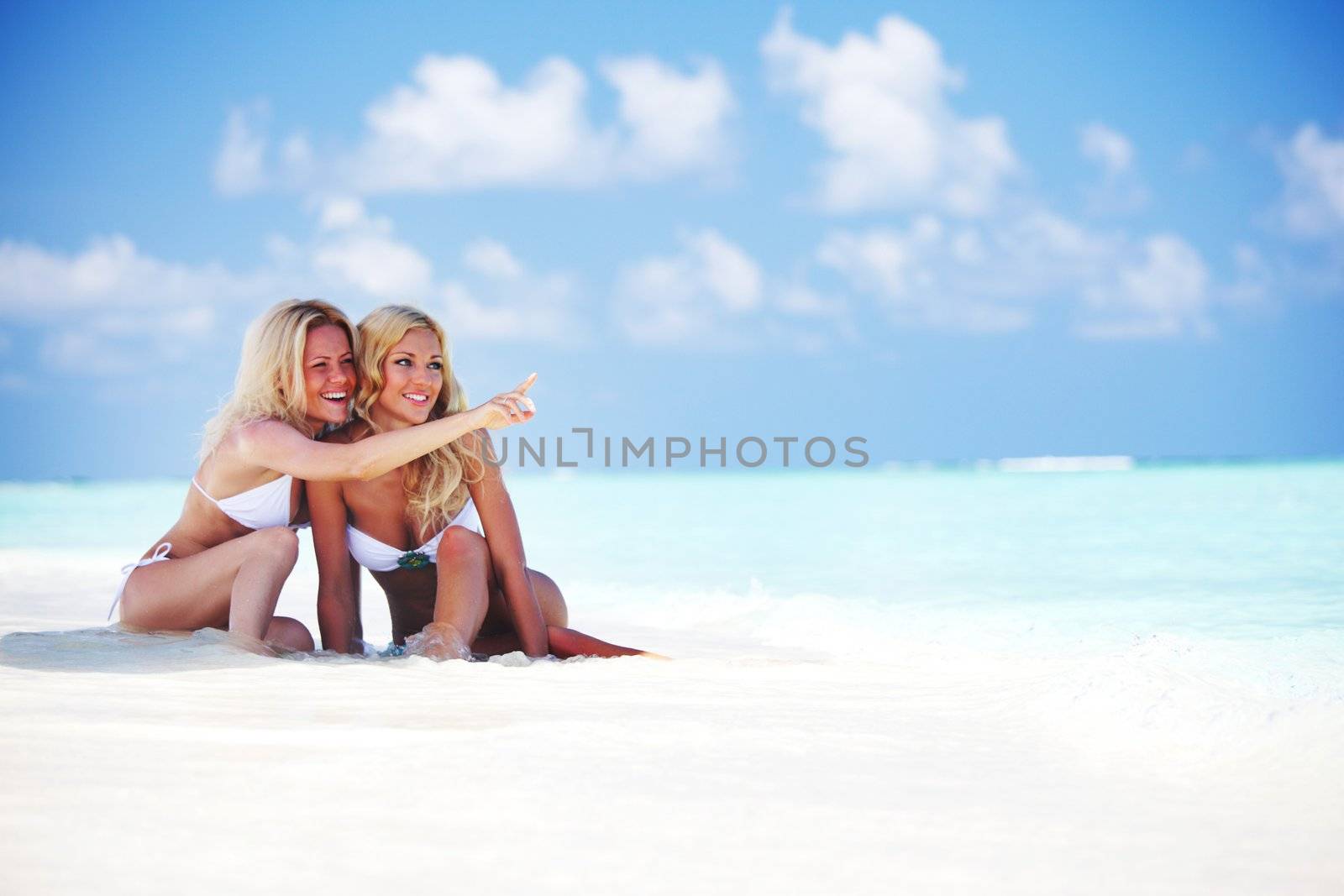 Two girls sitting on the ocean coast