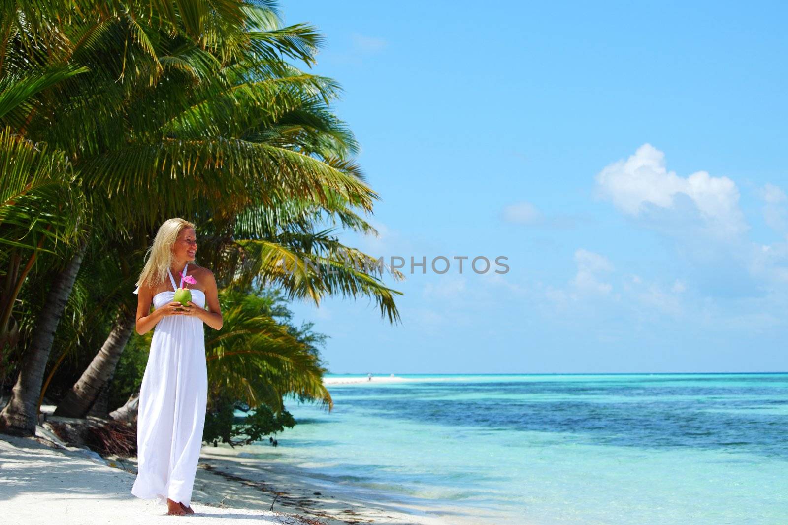 woman with a coconut cocktail on a tropical shore