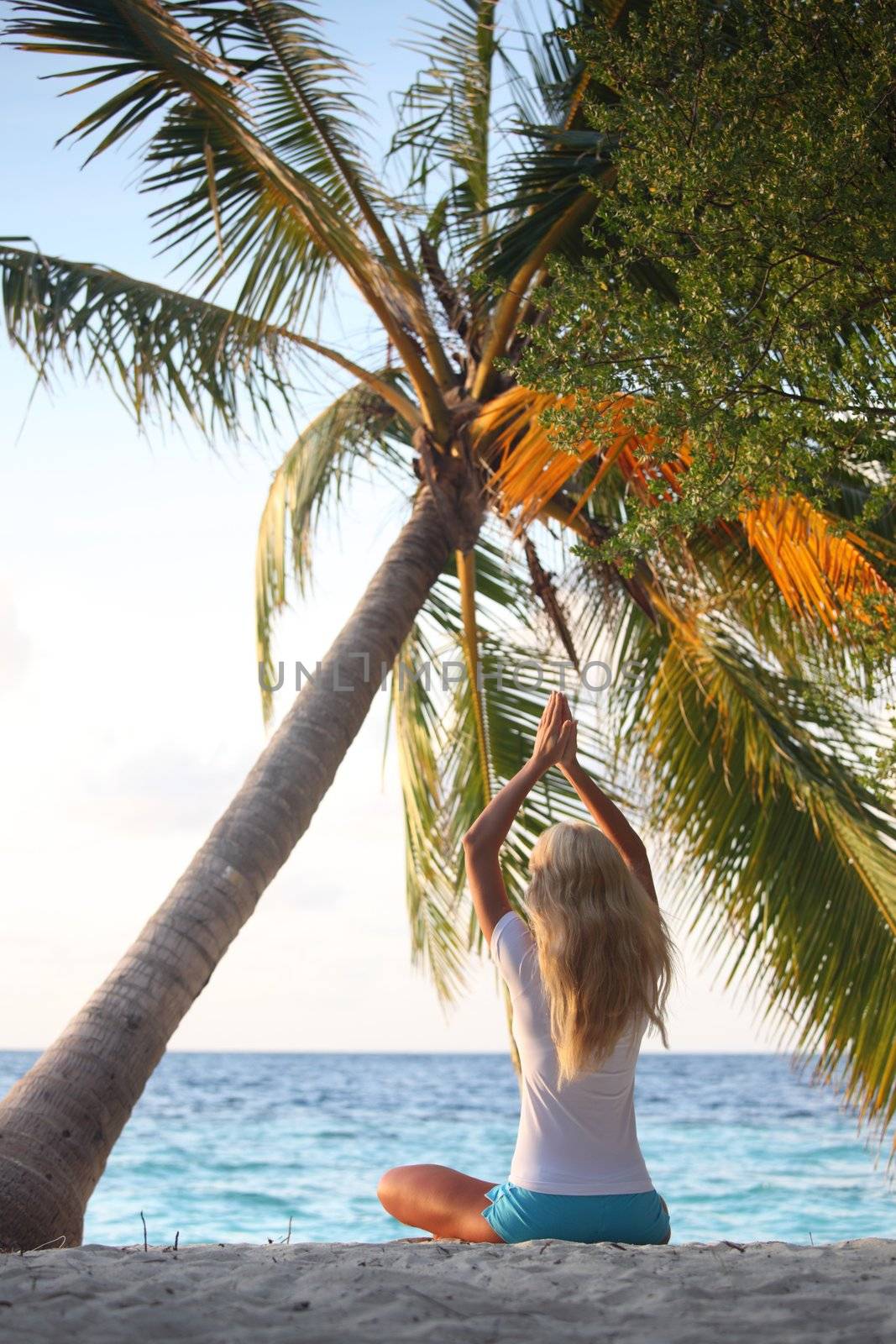 yoga woman on sea coast under palm