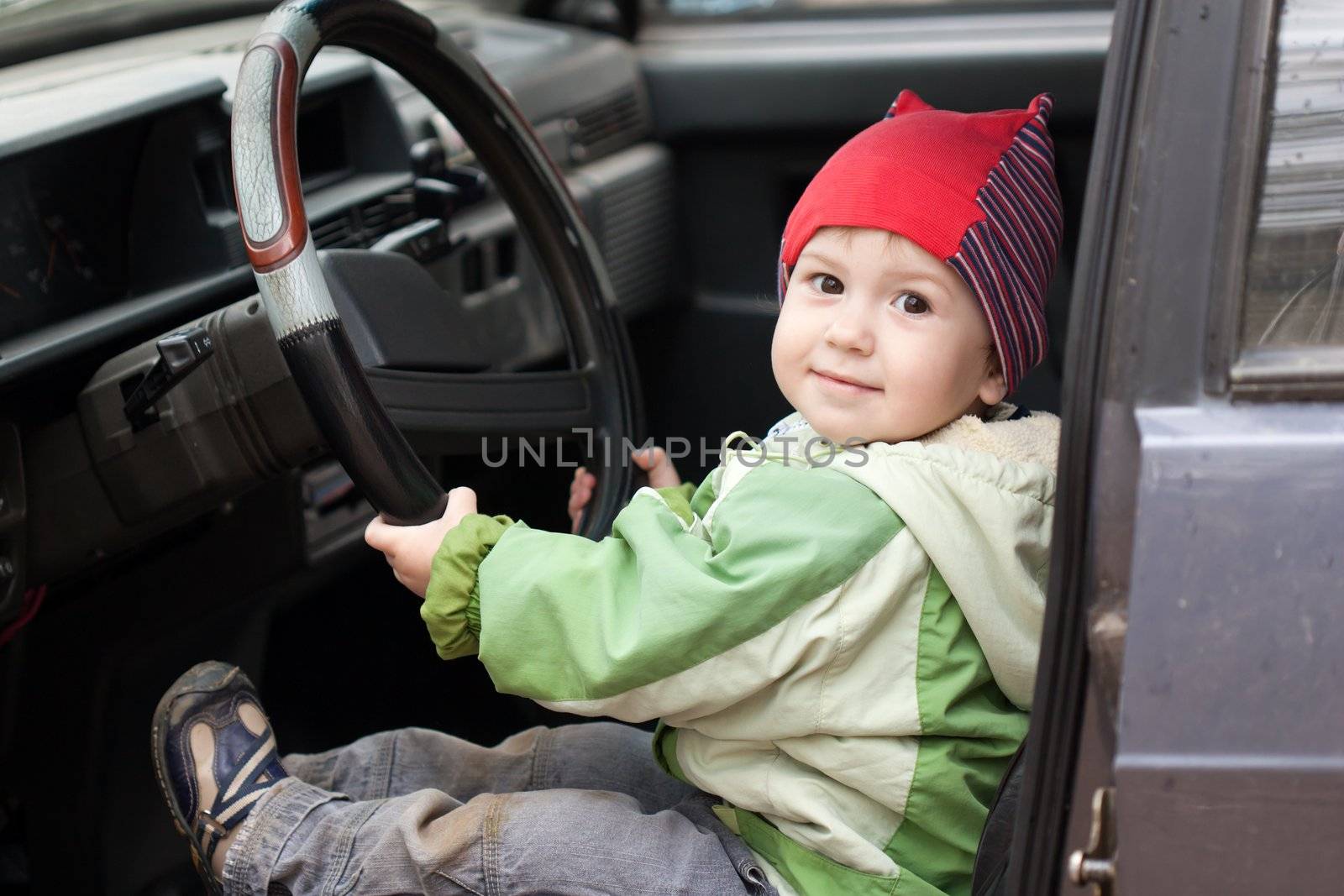 Little smiling child boy driving sport car vehicle