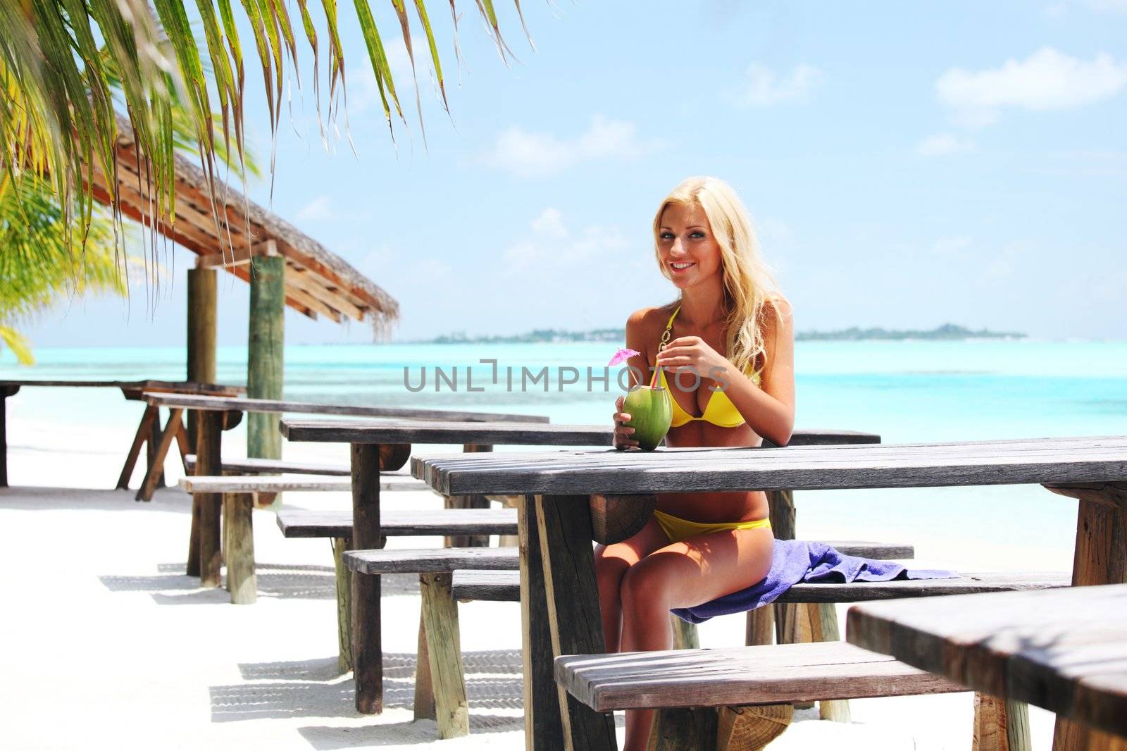 woman sitting in a tropical cafe on the background of a  palm trees and sky and sea