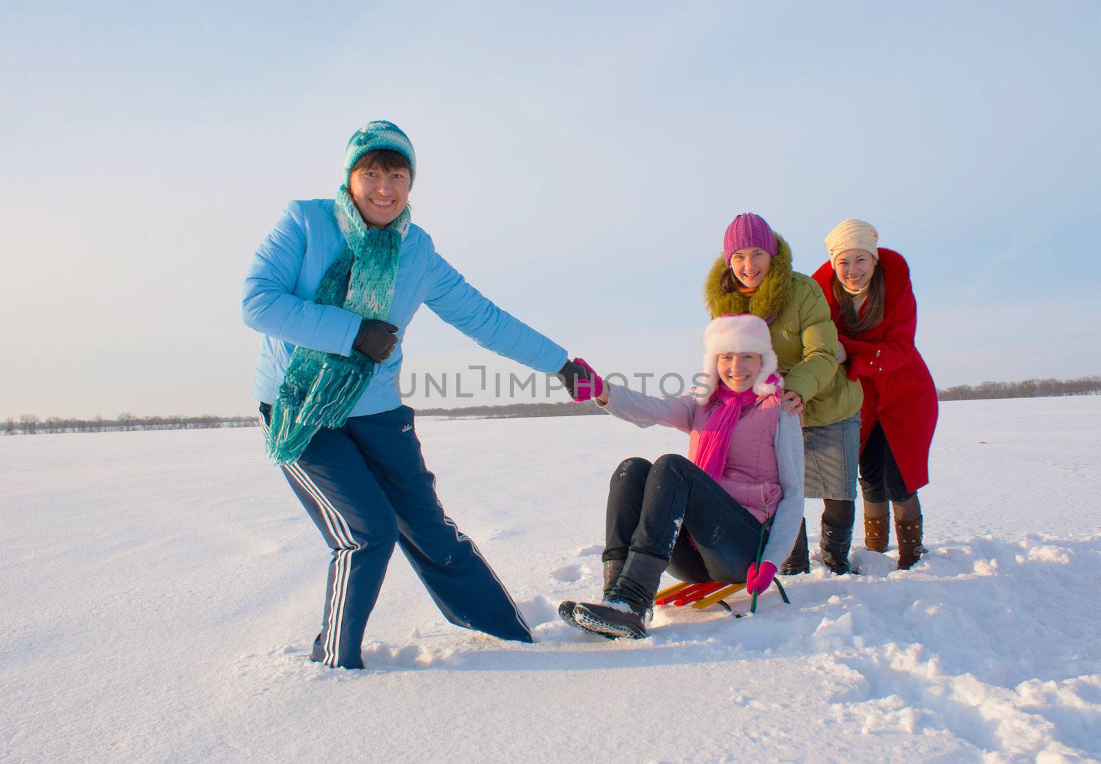 Four happy ladies sledding at the winter time 